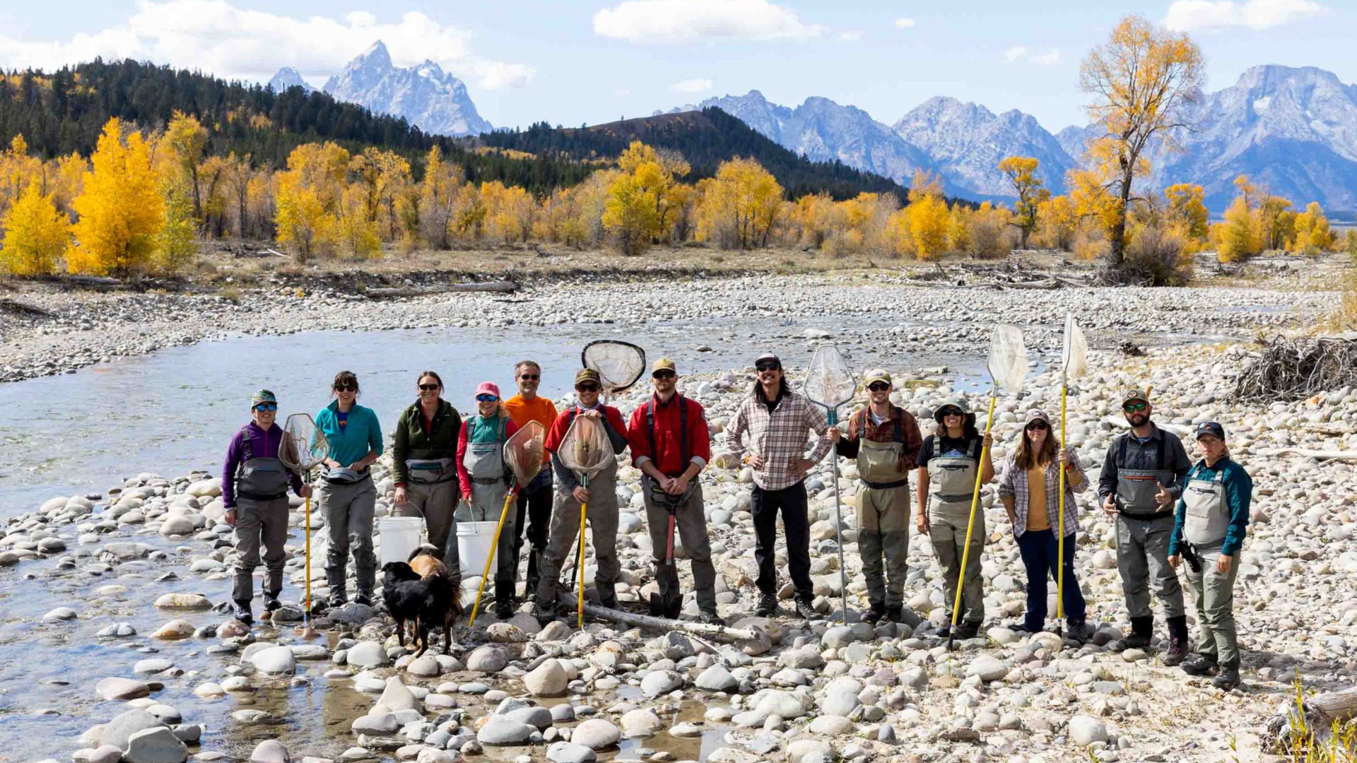 A group of volunteers stands in front of a lake.