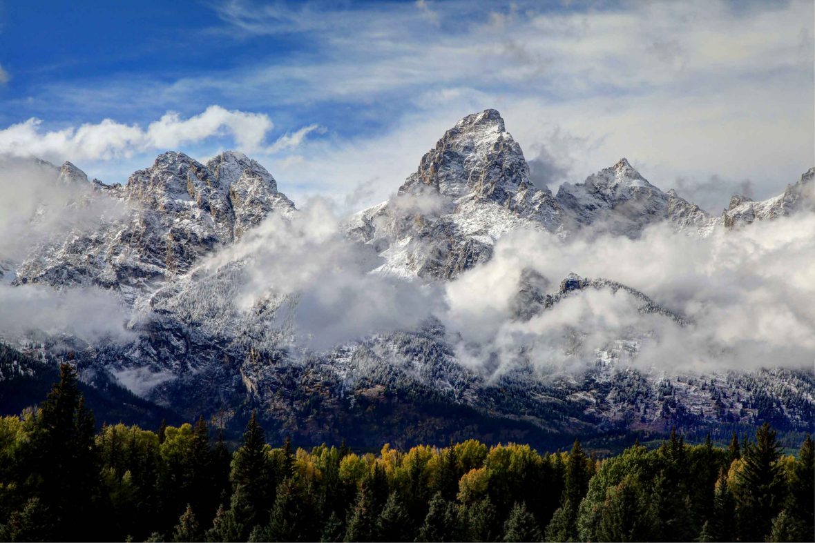 Snow-covered mountains in the background and trees in the foreground.